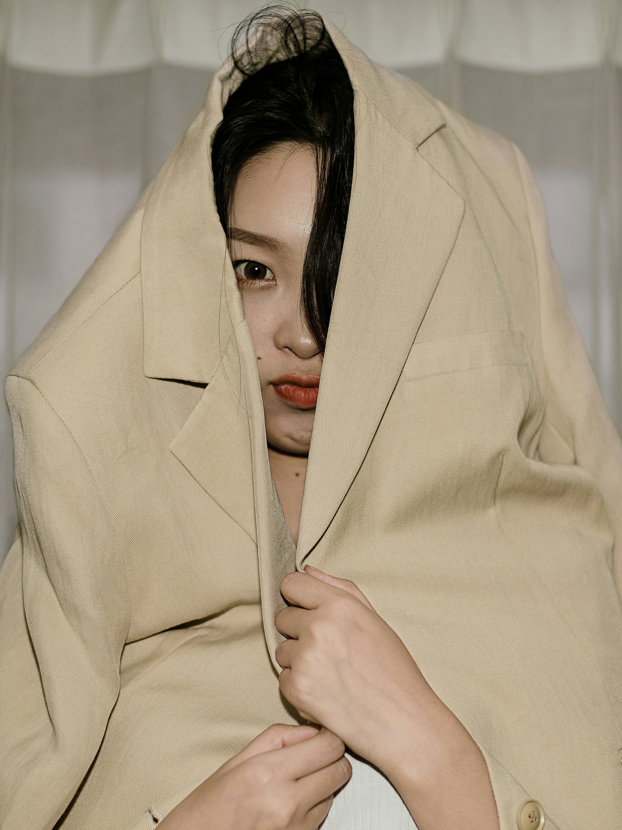 woman in brown coat covering her face with brown coat